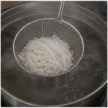 加入主料AI 拟真教学图：真实烹饪过程照片：必须表现“加入主料”。画面应对应动作：加入米粉，煮或炒到开始变软并吸收汤汁。；加入材料：米粉；视觉标准：主料表面变色、变软或开始吸收汤汁。
