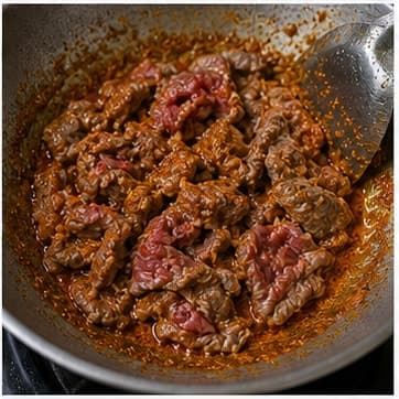 快炒牛肉AI 拟真教学图：真实烹饪过程照片：必须表现“快炒牛肉”。画面应对应动作：加牛肉片快速翻炒。；加入材料：牛肉片；视觉标准：牛肉外层变色，中心仍嫩。